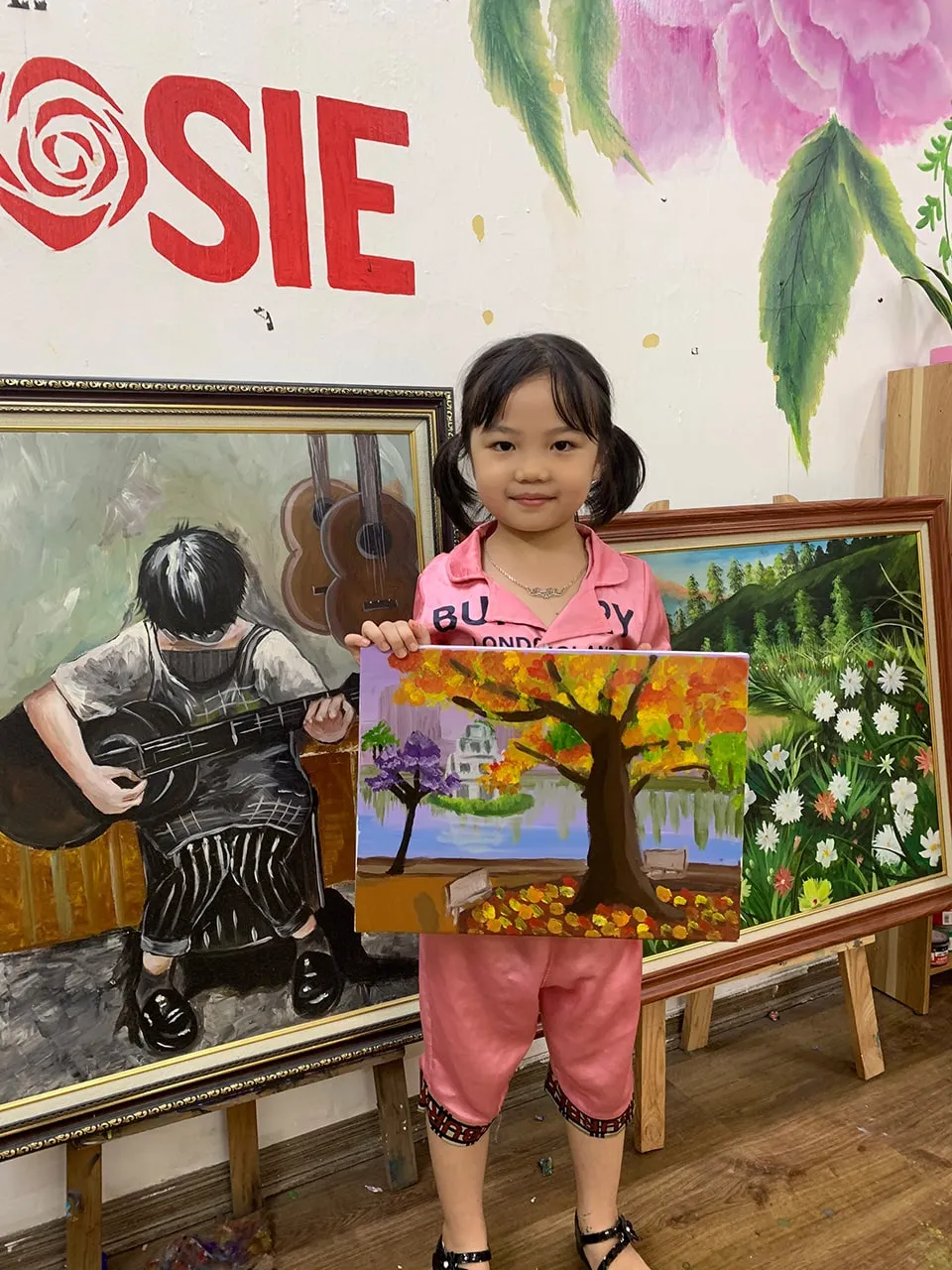 alt: Bé học viên tự hào khoe bức tranh vẽ của mình