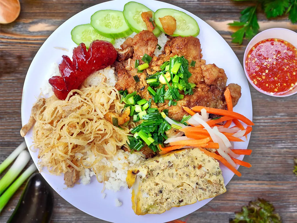 Đĩa cơm tấm đầy đủ các thành phần chính: sườn, bì, chả, mỡ hành và đồ chua.